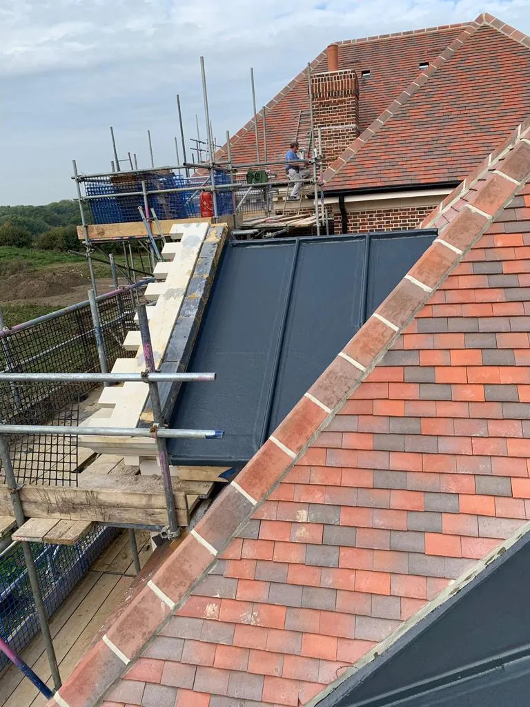 New plain clay tile roof with flat roof section and scaffold — Never Felt Better Roofing, Surrey