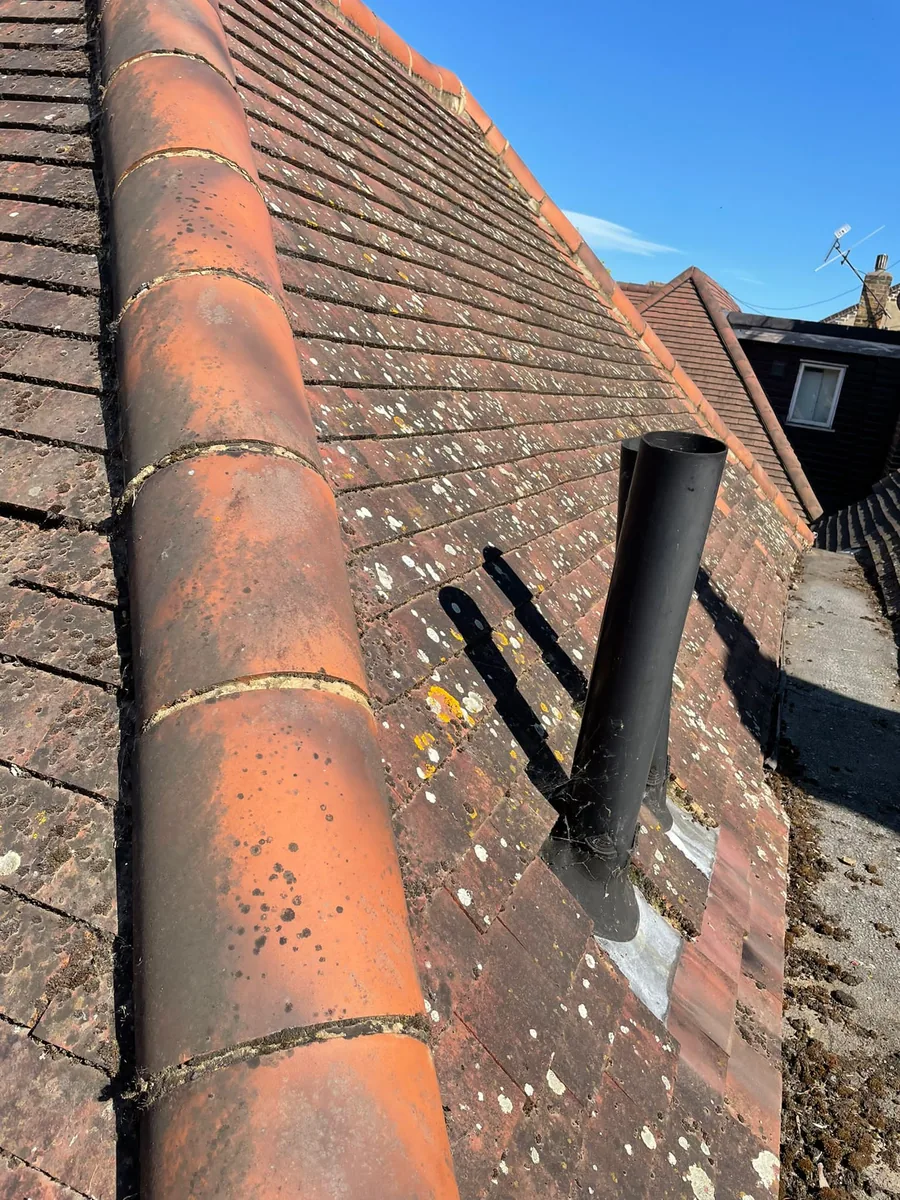 Worn clay tile roof with lichen growth and vent pipe — roof inspection in Surrey